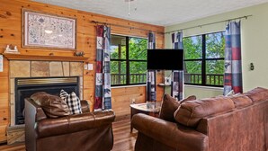 Een gezellige woonkamer met een open haard, leren banken, een flatscreen televisie en een kaart aan de wand.