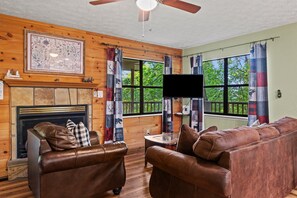 Ein gemütliches Wohnzimmer mit Kamin, Ledersofas, einem Flachbildfernseher und einer Karte an der Wand.