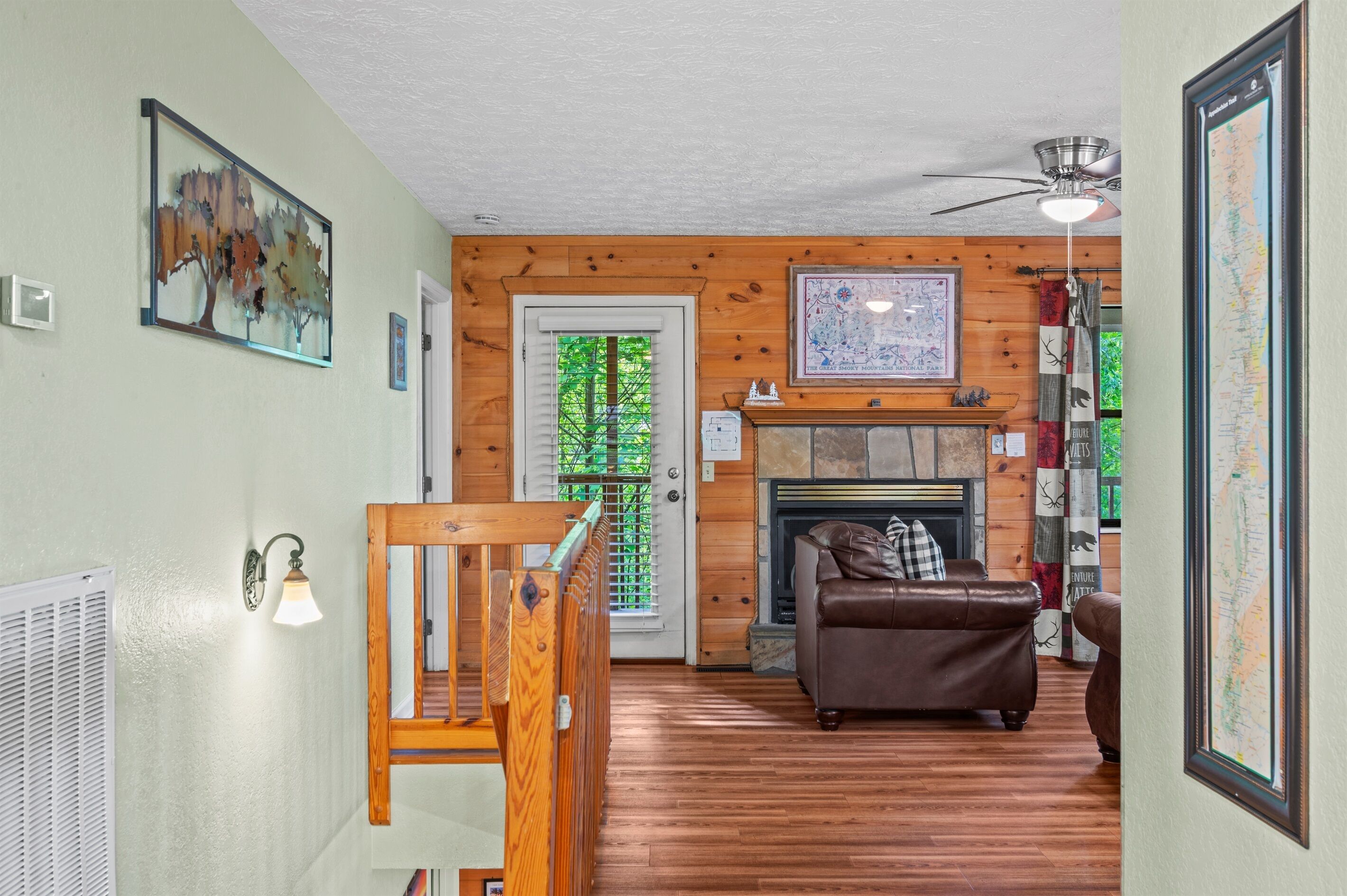 Un intérieur en bois avec une cheminée, un canapé en cuir marron et un escalier.