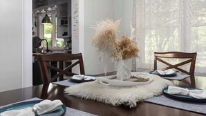A dining table set with plates, a vase with dried flowers, and a fluffy rug. - Spacious 4BR Home_Fenced Yard_Patio_BBQ Grill (Overland Park)