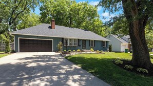 A residential house with a garage, a driveway, and a well-maintained lawn. - Spacious 4BR Home_Fenced Yard_Patio_BBQ Grill (Overland Park)