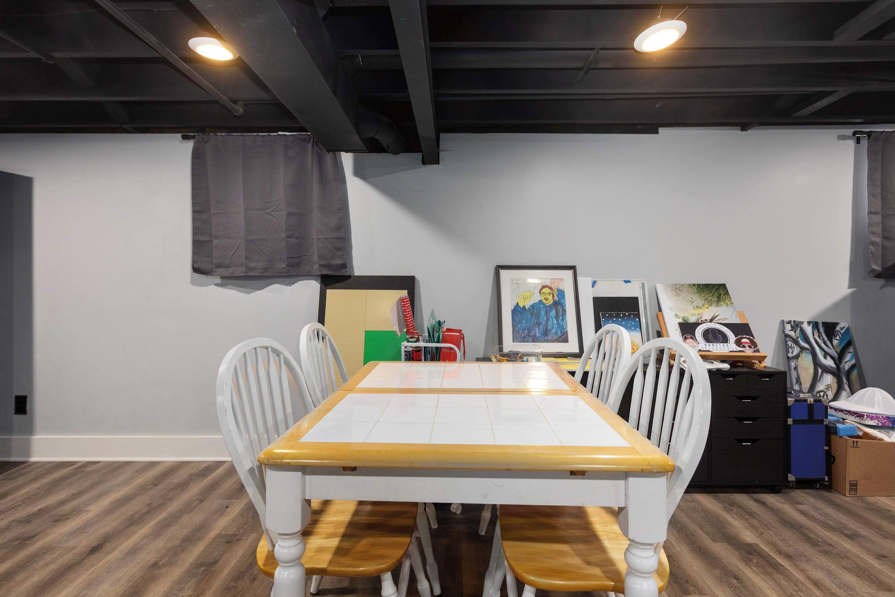 A dining area with a table and chairs, a ceiling with exposed beams, and artwork on the walls.