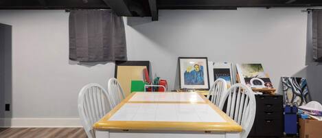 A dining area with a table and chairs, a ceiling with exposed beams, and artwork on the walls.