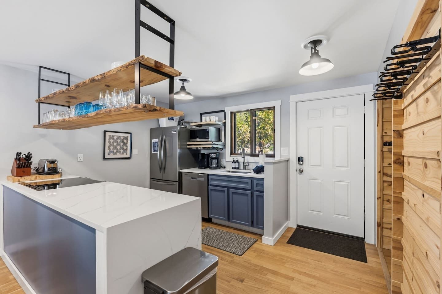A modern kitchen with a central island, built-in appliances, and wooden shelving.