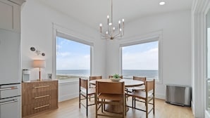 Eine moderne Küche mit Essbereich, großen Fenstern und Blick auf den Strand.