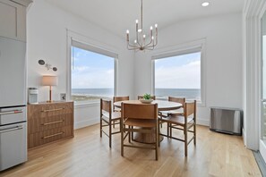 Eine moderne Küche mit Essbereich, großen Fenstern und Blick auf den Strand.