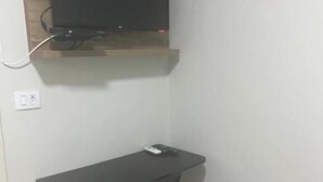 Een kleine kamer met een bureau, stoel en een wandtelevisie.