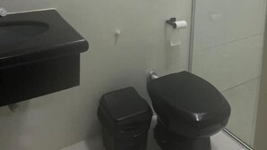 Een badkamer met een zwart wastafel, toilet en douchecabine.