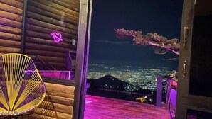 A room with a bed, a laptop, a chair, and a view of a cityscape at night. - Romero Glamping y Cabañas (Cali)