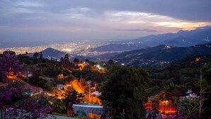 A panoramic view of a city at dusk with illuminated buildings and distant mountains. - Romero Glamping y Cabañas (Cali)