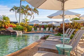 A poolside area with lounge chairs, umbrellas, and tropical plants. - Kiahuna 216 At Koloa Kai Ocean View  PBAC Access (Koloa)