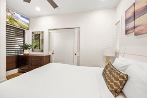 A bedroom with a bed, a dresser, a mirror, a TV, and a door. - Kiahuna 216 At Koloa Kai Ocean View  PBAC Access (Koloa)
