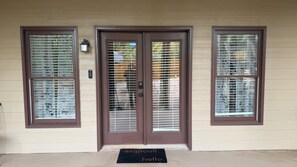 A front door with a brown frame, a doormat with 'goodbye' and 'hello' text, and a mailbox on the wall.