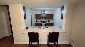 A kitchen with a central island, two bar stools, and a microwave above the stove.