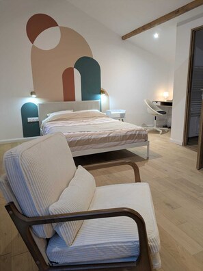 A modern bedroom with a bed, two bedside tables, a chair, and a large abstract wall art piece.