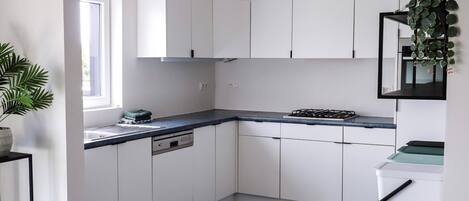 A modern kitchen with white cabinets, a black countertop, and a gas stove.