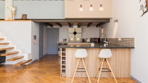 A modern kitchen with a central island, bar stools, and a staircase leading to an upper level. - Stunning Apartment - 4br-7p - Crequi (Lyon)