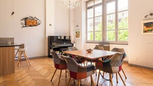 A dining area with a wooden table, chairs, a piano, and a large window. - Stunning Apartment - 4br-7p - Crequi (Lyon)