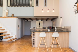 A modern kitchen with a central island, bar stools, and a staircase leading to an upper level. - Stunning Apartment - 4br-7p - Crequi (Lyon)