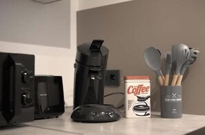 Une machine à café, un appareil de la marque Philips, une boîte de café et des ustensiles sur un plan de travail.