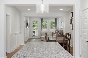 A kitchen with a granite countertop, wooden dining table, and chairs. - Tiger Walk Townhouse (Auburn)