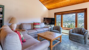 Ein Wohnzimmer mit Holzboden, einer Sofagarnitur, einem Couchtisch und einem Fernseher.