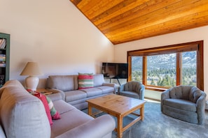 Ein Wohnzimmer mit Holzboden, einer Sofagarnitur, einem Couchtisch und einem Fernseher.