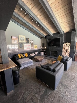 A modern living room with a fireplace, stone flooring, and a lofted ceiling with exposed beams. - 2+Loft Canyon Lodge Cabin - Pool/Jacuzzi/Parking! (Mammoth Lakes)