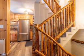 A wooden staircase with a rustic design leading to a kitchen area with wooden cabinets and stainless steel appliances. - 2+Loft Canyon Lodge Cabin - Pool/Jacuzzi/Parking! (Mammoth Lakes)