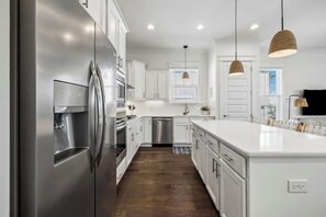 A modern kitchen with white cabinetry, stainless steel appliances, and pendant lighting. - Newly Listed Home with Community Pool Access, LSV, Bikes, Grill and Firepit (Santa Rosa Beach)