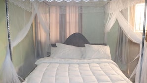 Una cama con dosel, cabecera y cortinas.