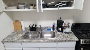 A kitchen with a granite countertop, stainless steel sink, white cabinets, a stove, and a microwave. - Cozy Cove #6 (Apple Valley)