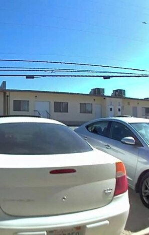 A parking lot with two cars, a building with a flat roof, and power lines in the background.