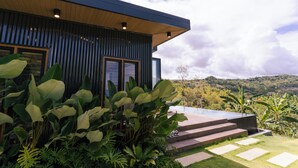 Un bâtiment moderne doté d’une terrasse en bois et offrant une vue sur un paysage luxuriant.
