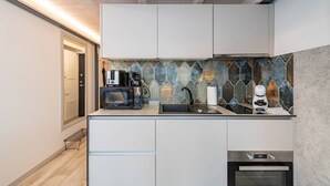 A modern kitchen with a stone backsplash, a coffee machine, a microwave, and a built-in oven. - Sunshine Loft by Polo Apartments (Kaunas)