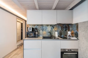 A modern kitchen with a stone backsplash, a coffee machine, a microwave, and a built-in oven. - Sunshine Loft by Polo Apartments (Kaunas)