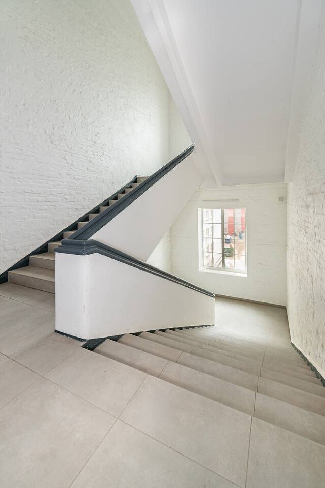 A staircase in a room with white walls and a window.
