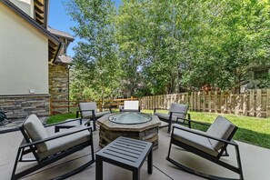 Eine Terrasse im Freien mit einem Steinkamin, vier Stühlen und einem Tisch.
