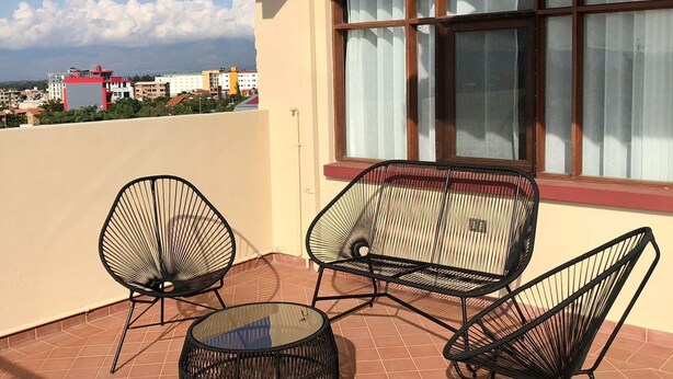 Une terrasse avec une table, deux chaises et une lampe.
