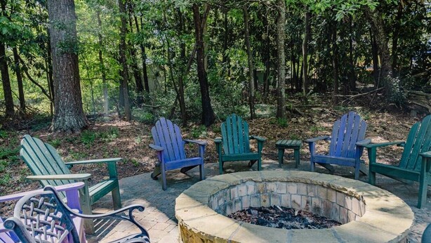 Un foyer entouré de fauteuils Adirondack, situé dans un espace boisé.