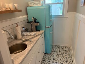 Cocina compacta con lavamanos, encimera y refrigerador verde azulado.
