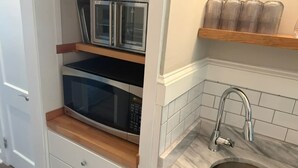 Une cuisine équipée d’appareils électroménagers intégrés, dotée d’un plan de travail en bois, d’un évier en acier inoxydable et d’un dosseret carrelé.