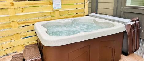 Een hottub met treden, een houten omheining en een waarschuwingsbord.
