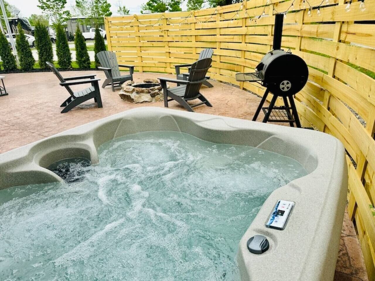 Una vasca idromassaggio con pannello di controllo, circondata da area relax esterna e barbecue.