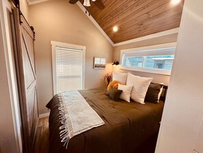 Ein Schlafzimmer mit einem Bett, einem Fenster und einer Holzbalkendecke.