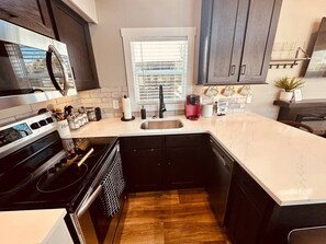 Eine kompakte Küche mit eingebautem Herd, Spüle und dunklen Schränken.