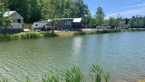 Un lac avec un quai, des camping-cars et un bâtiment doté d’une grande fenêtre.