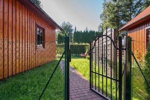 A wooden cabin with a paved pathway leading to a gated entrance. - Scandinavian Cottage With Private Garden (Choczewo)