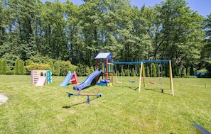 A playground with a slide, swings, and a climbing structure. - Scandinavian Cottage With Private Garden (Choczewo)