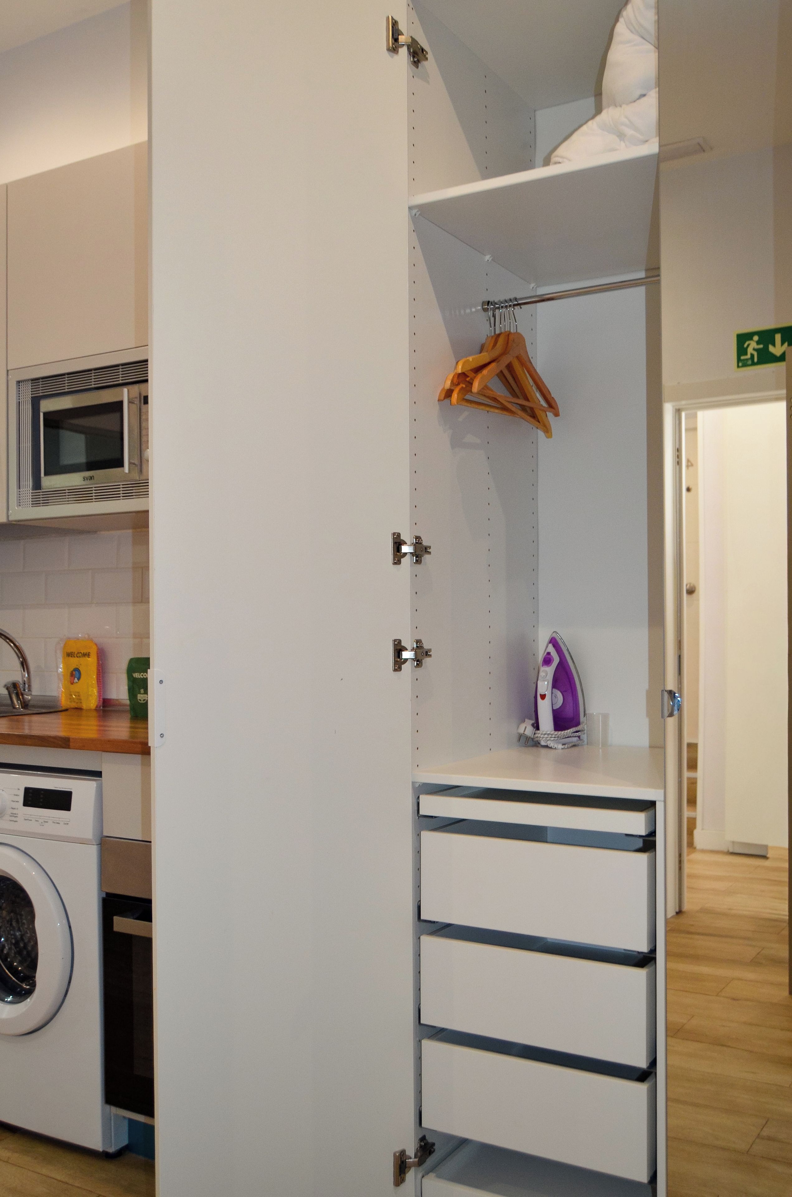 Una cocina equipada con microondas, lavadora y un tendedero.